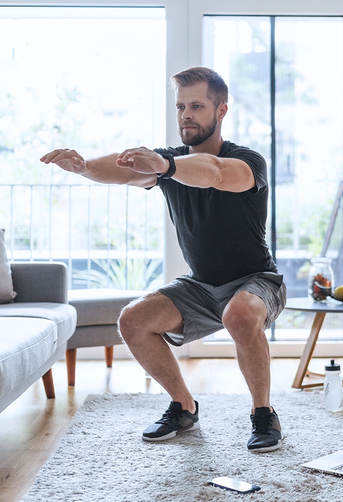 Man doing workout squats in his living room