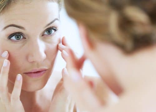 Woman looking at her skin in the mirror after wrinkle reduction